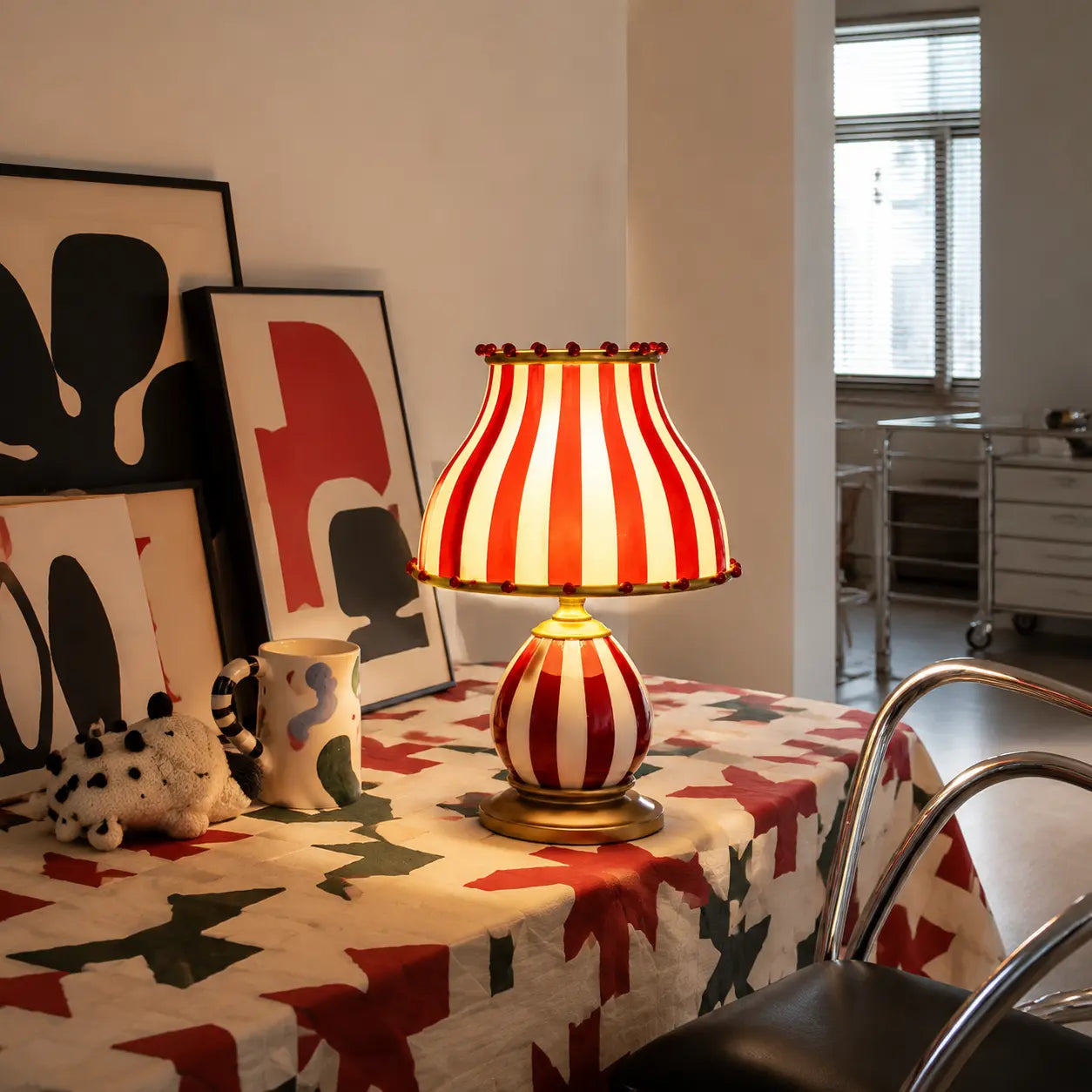 Odette striped table lamp glowing in a lived-in Nordic dining room with graphic textiles and art