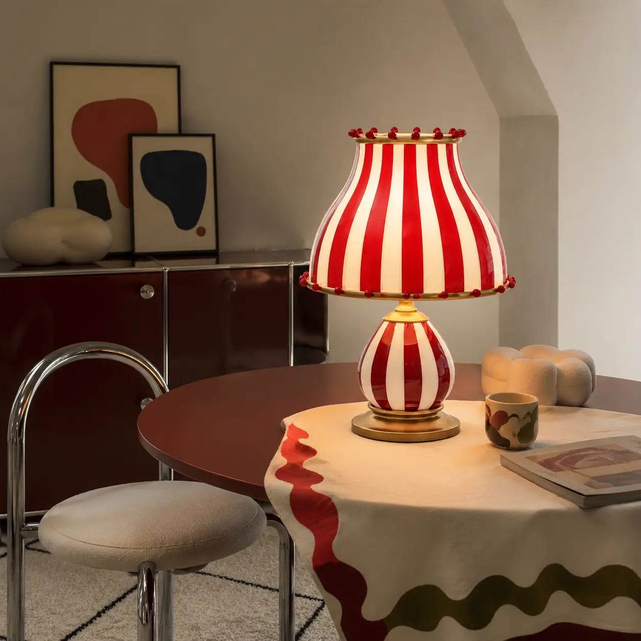 Odette striped table lamp on a burgundy metal table in a warm playful Nordic room