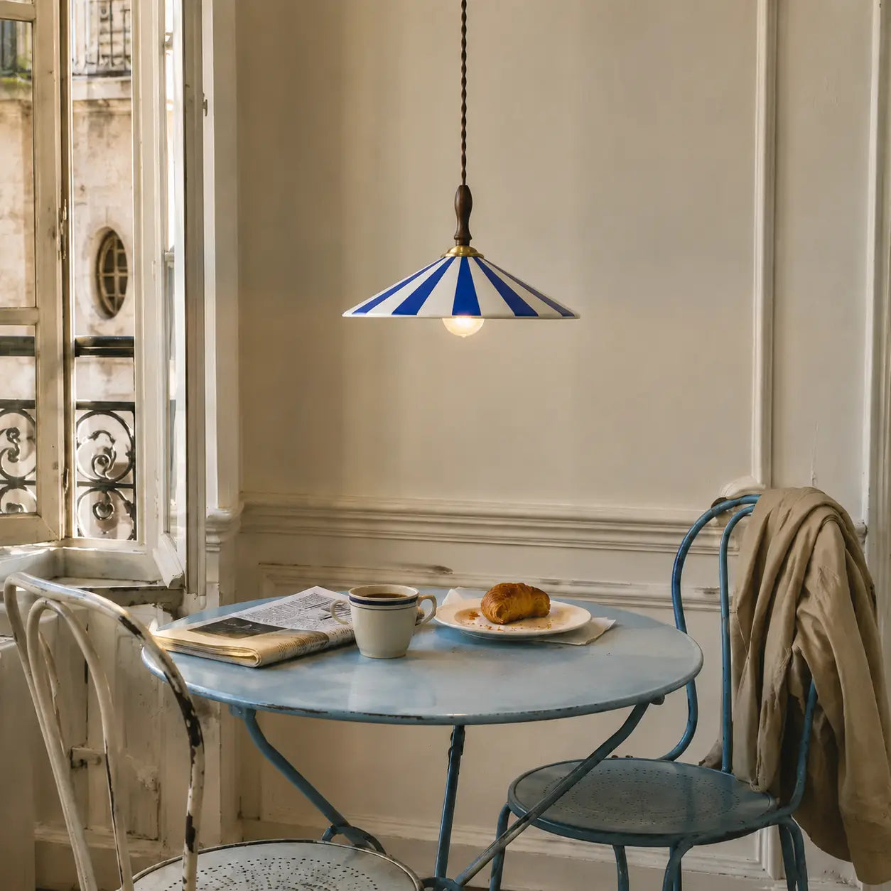 Blue Solenne pendant above a lived-in Parisian breakfast table
