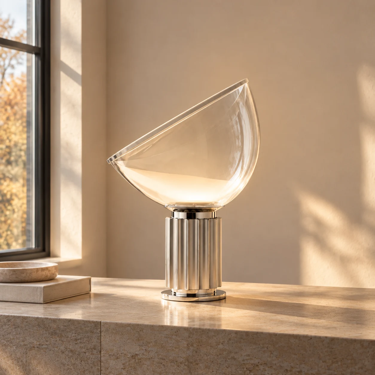 Illuminated silver Taci lamp by an autumn window