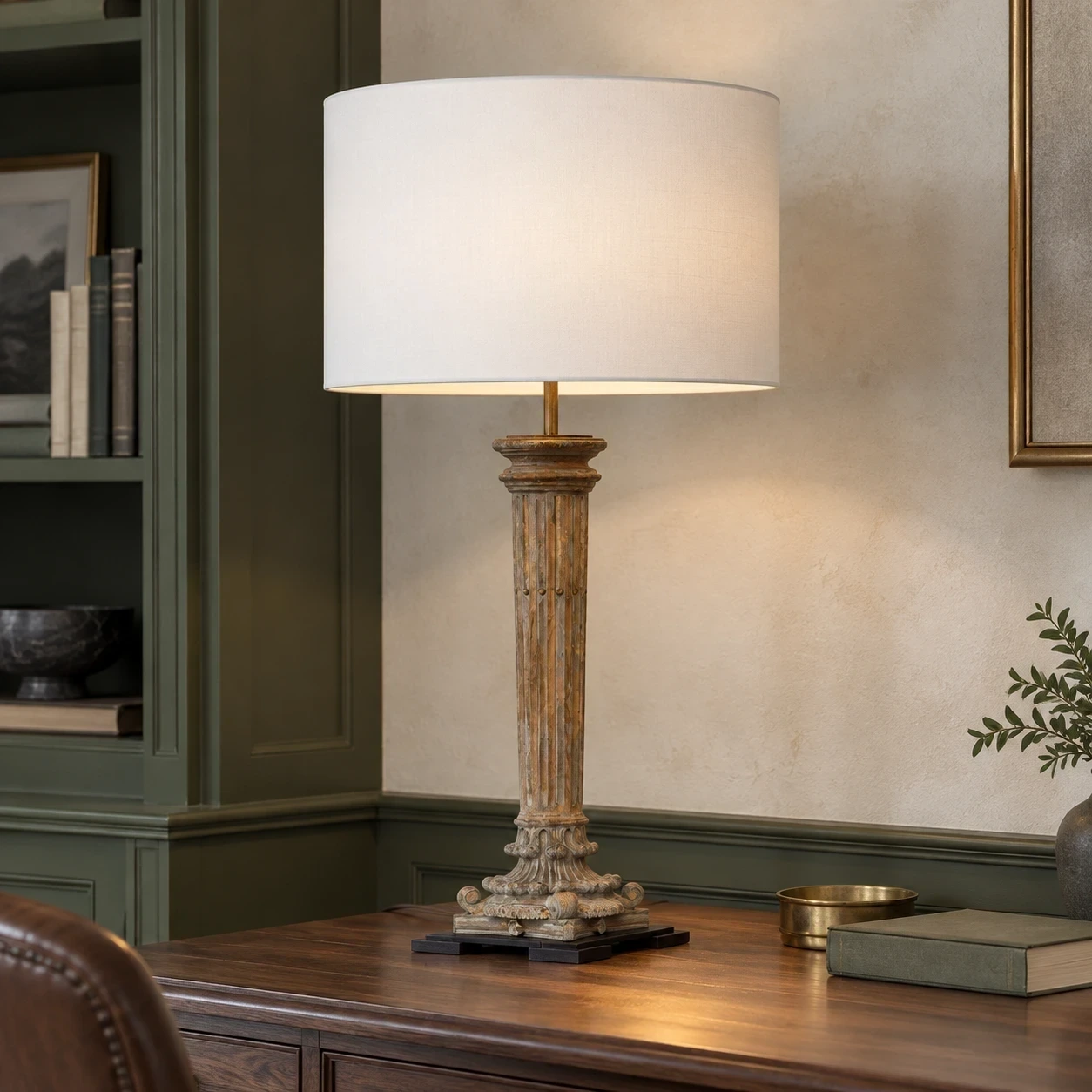 Aveline carved wood table lamp on a walnut desk against deep olive joinery