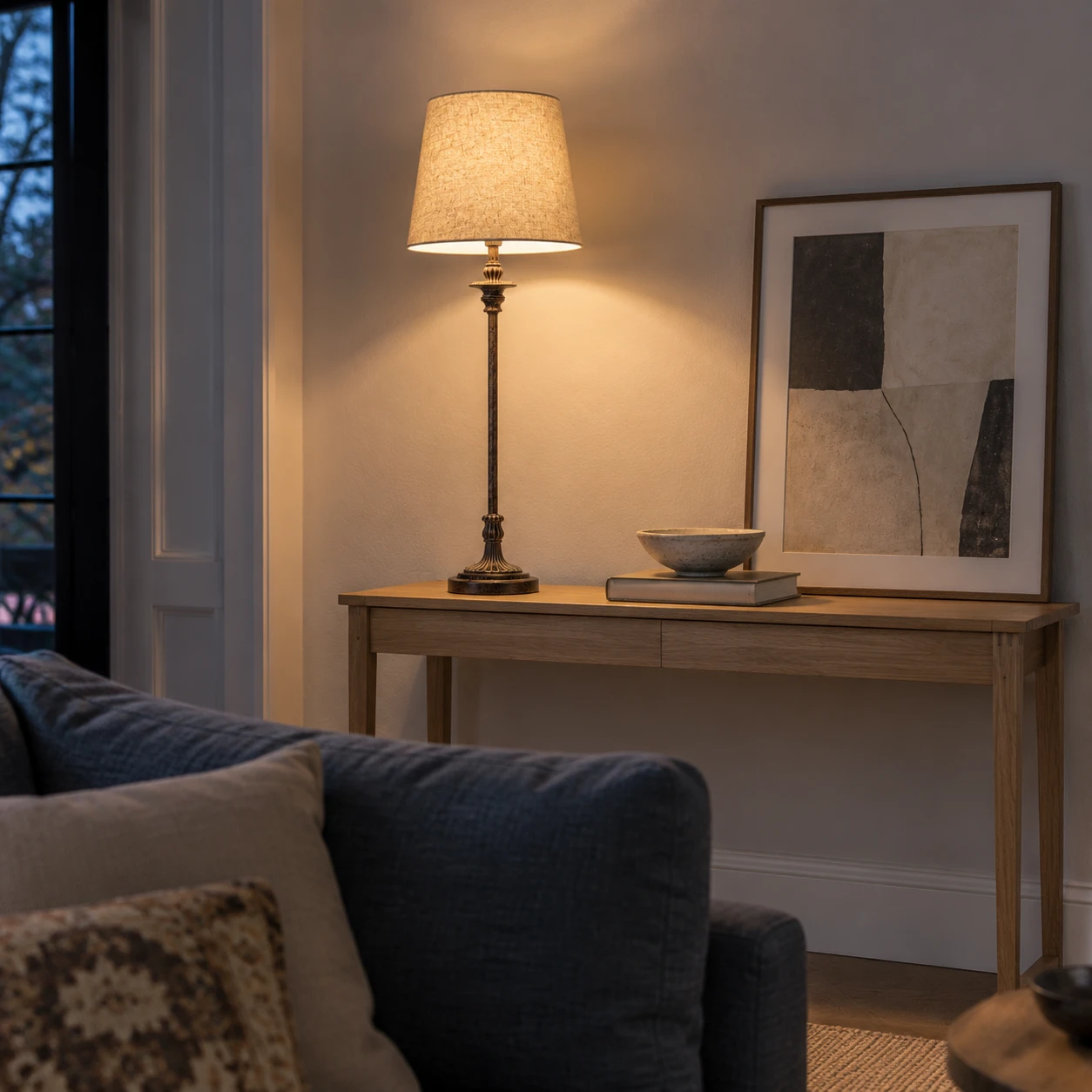Tall carved wood table lamp on a living room console at dusk