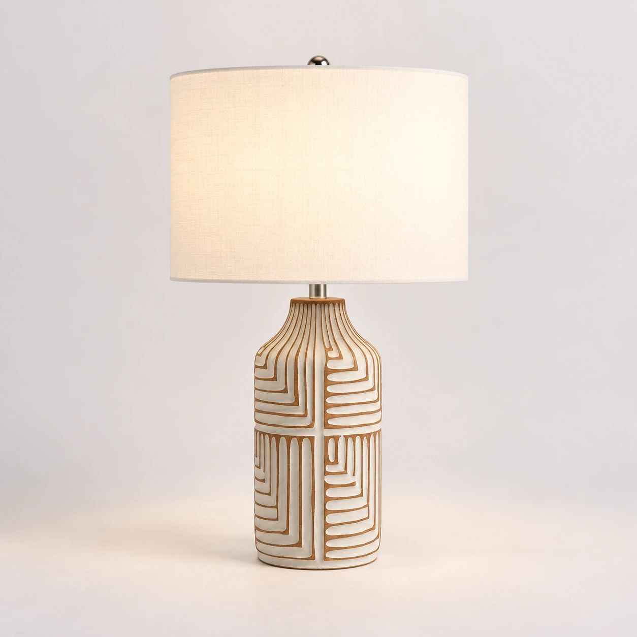 Odette carved wood table lamp switched on in a neutral studio