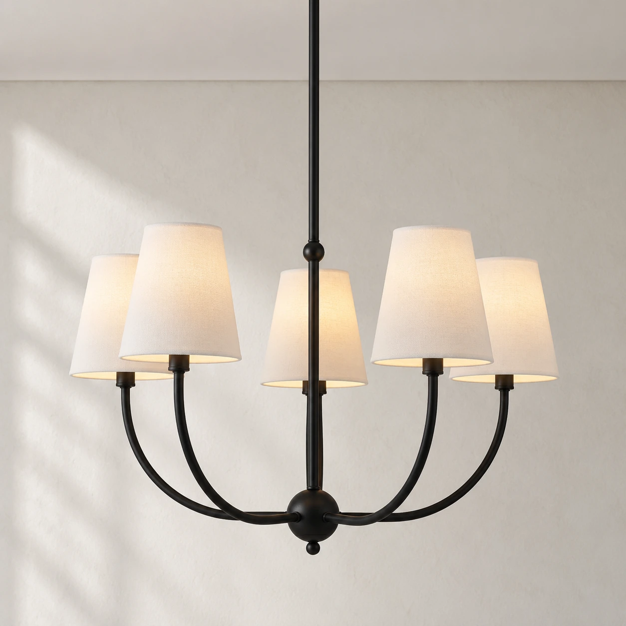 Vintage branch chandelier with fabric shades against a bright vintage architectural wall