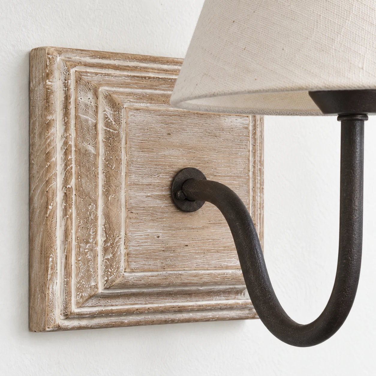 Close view of carved wood backplate, iron arm and woven fabric shade