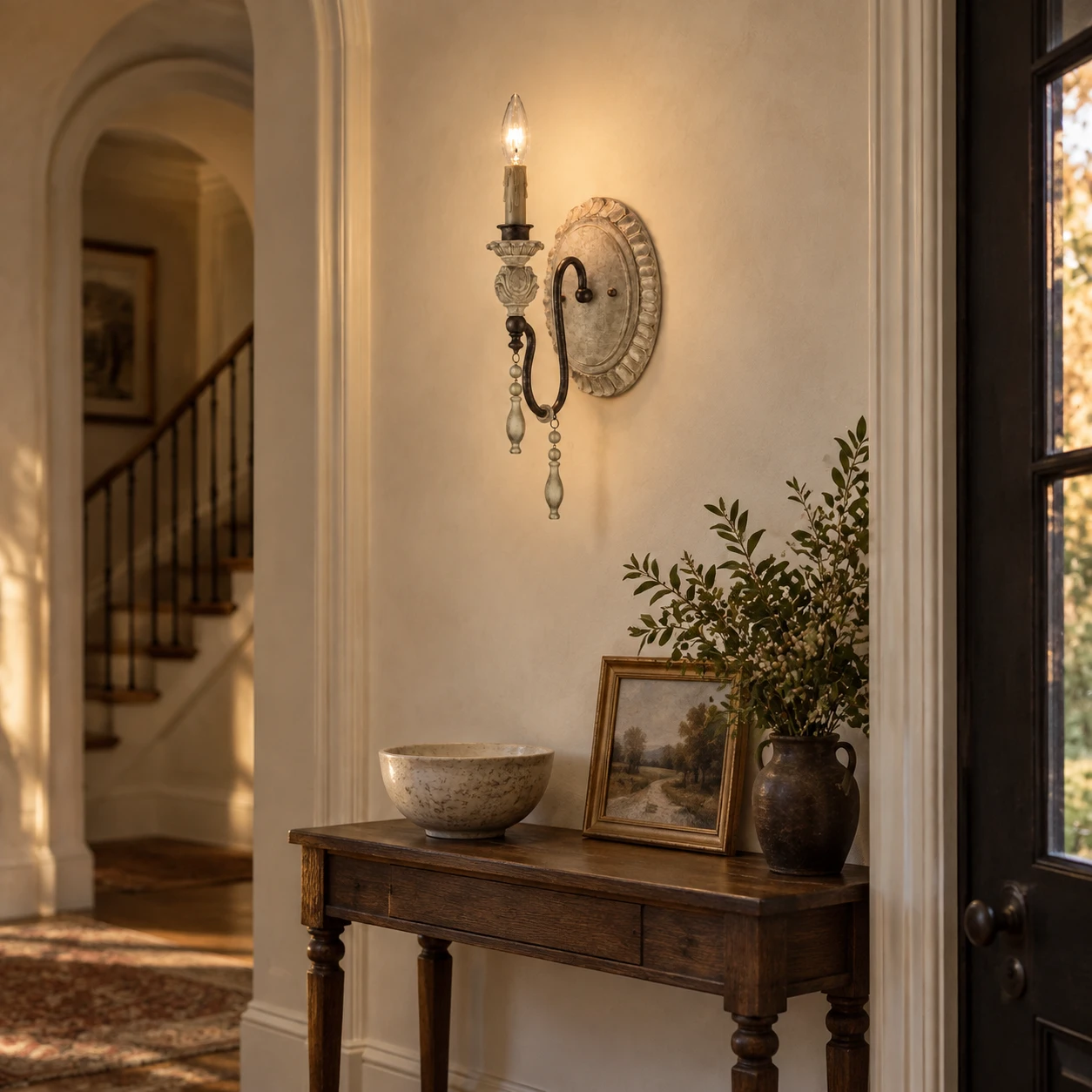 One-light carved wood wall sconce above an entryway console