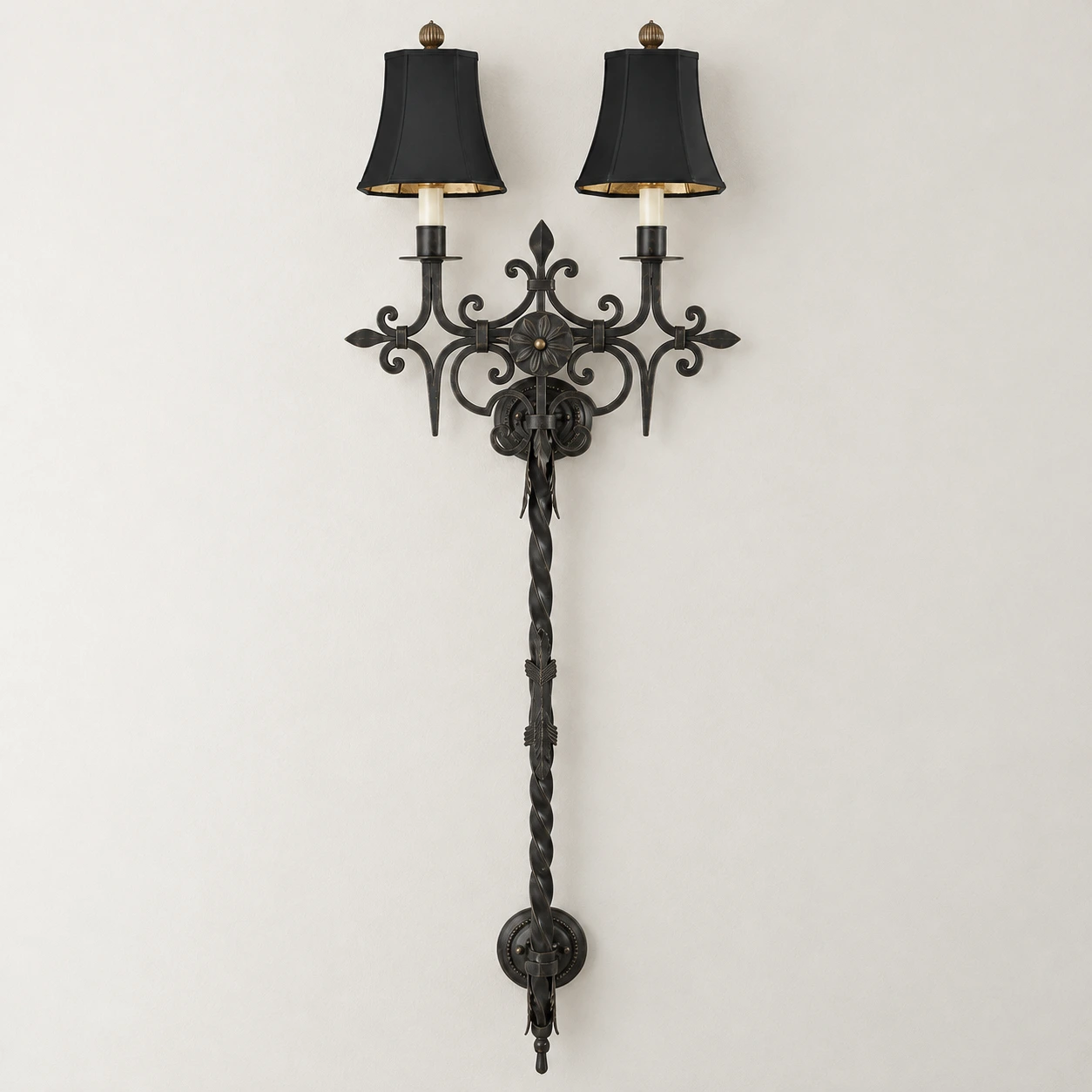 Black distressed iron wall sconce switched off in a neutral studio