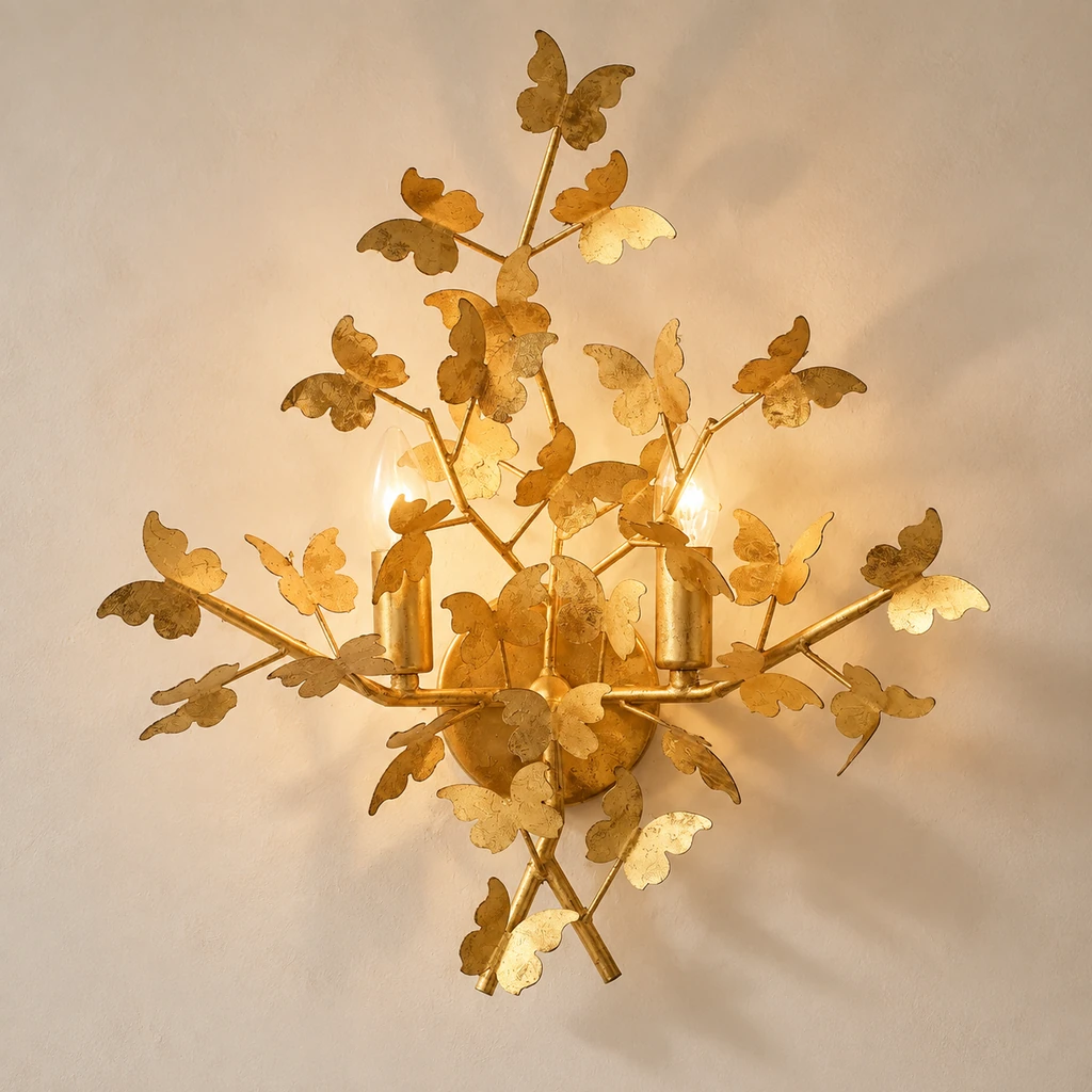 Nora sculpted gold-leaf butterfly wall light illuminated against pale plaster