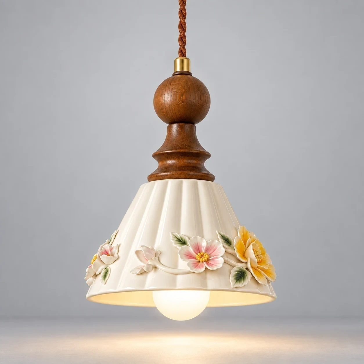 Vintage Floral Ceramic and Wood Pendant Light switched on in a neutral studio