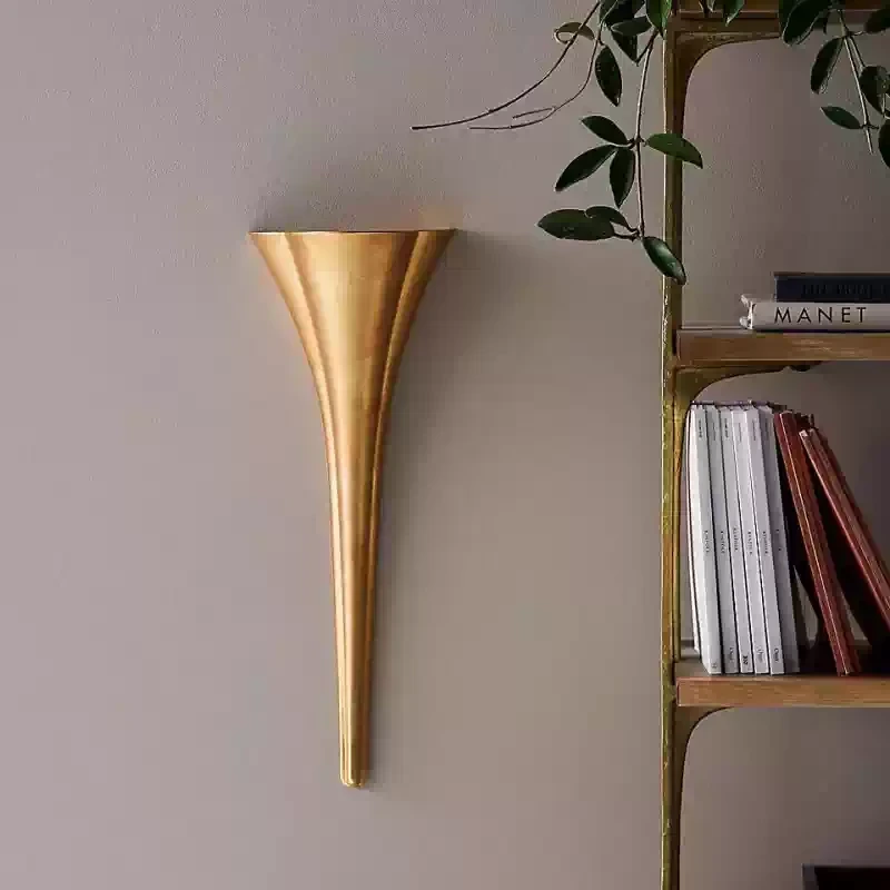 Brass tapered wall sconce beside a shelf and books