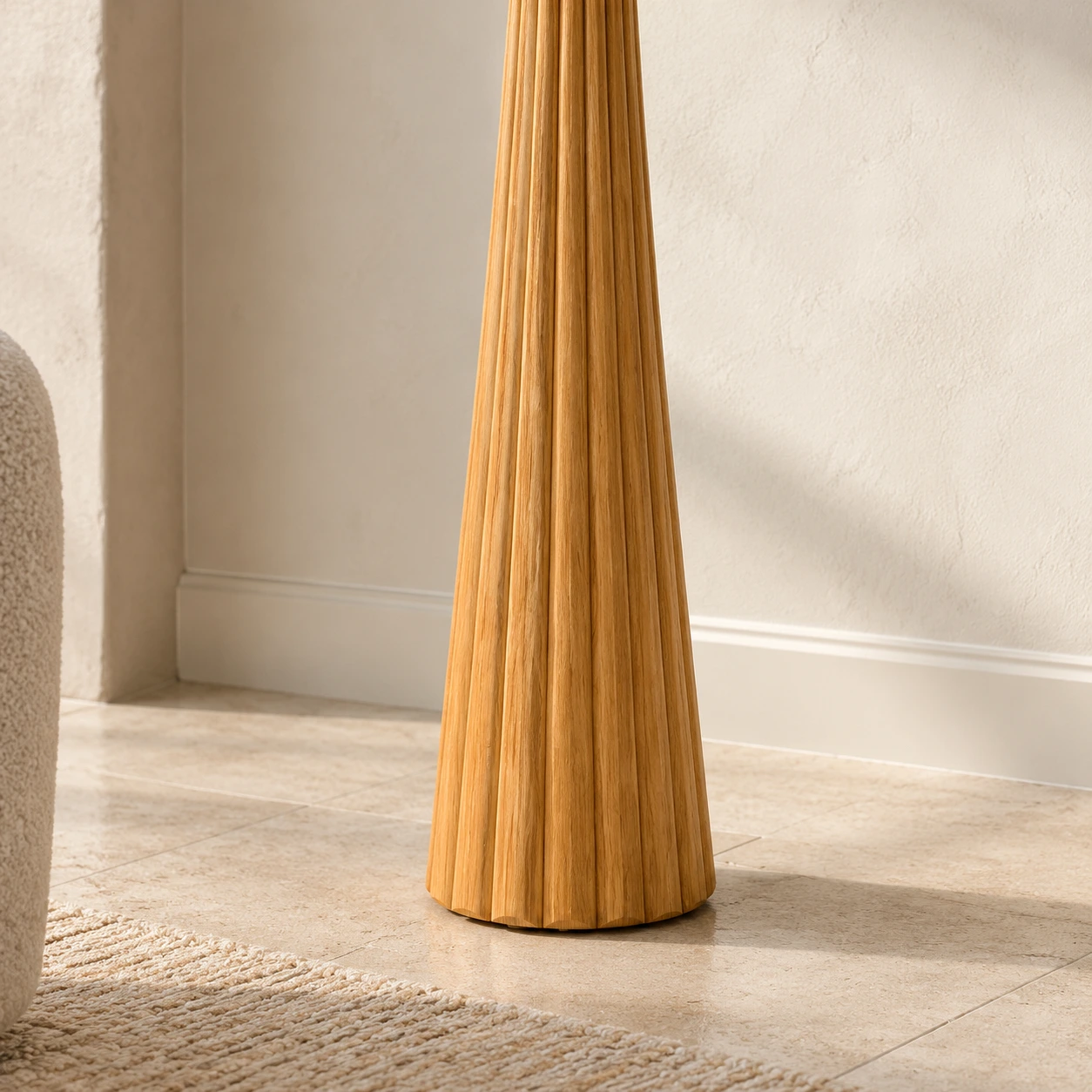 Close view of the Elodie lamp's fluted natural-wood base meeting a pale limestone floor