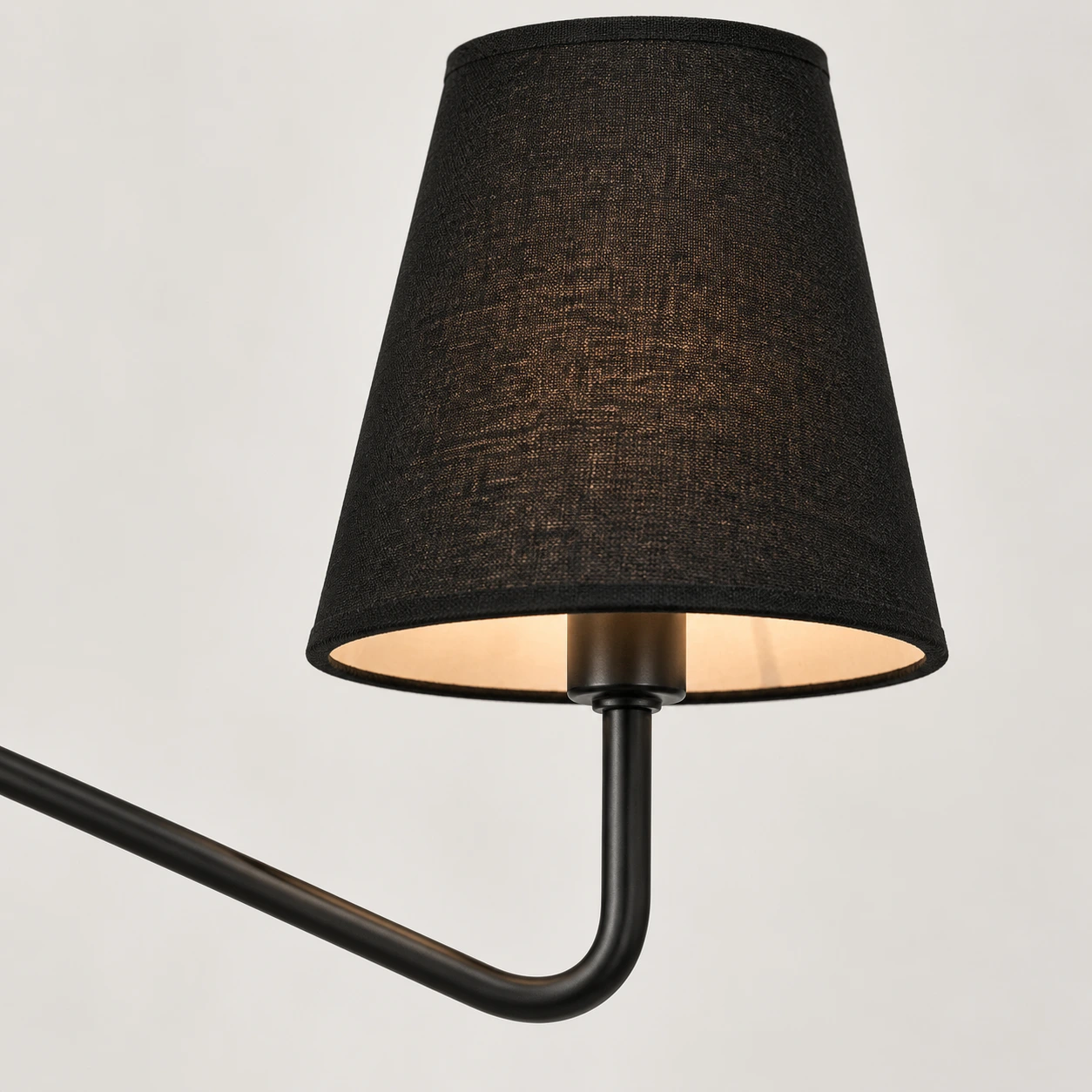 Close view of a black fabric shade, socket stem and curved arm
