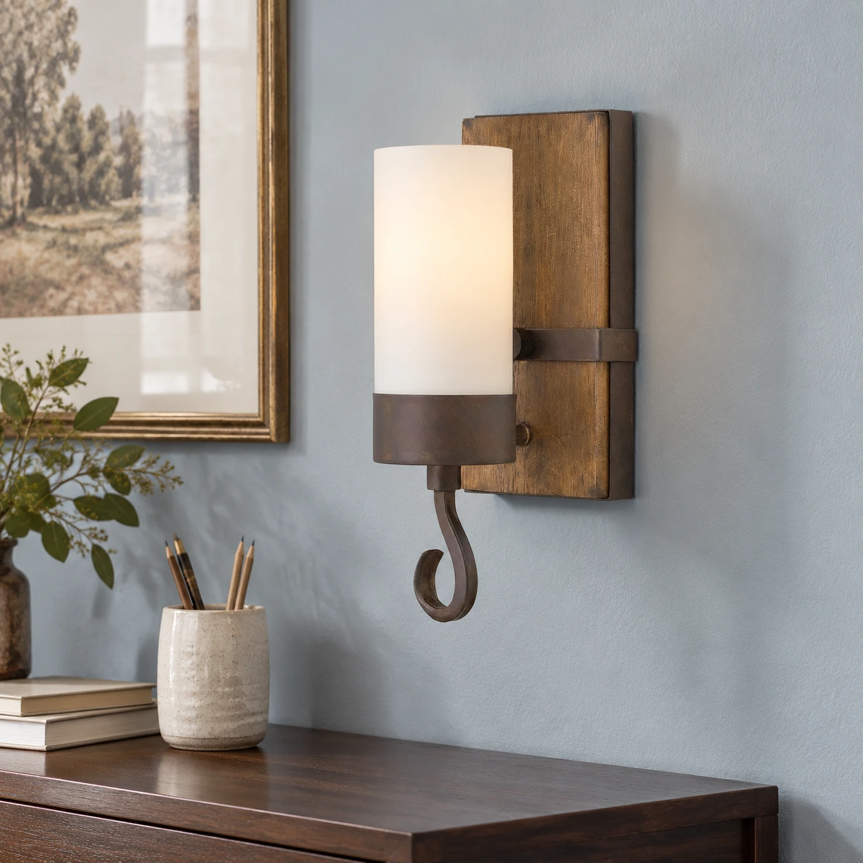Carved wood wall sconce above a walnut study console with a dusty blue wall