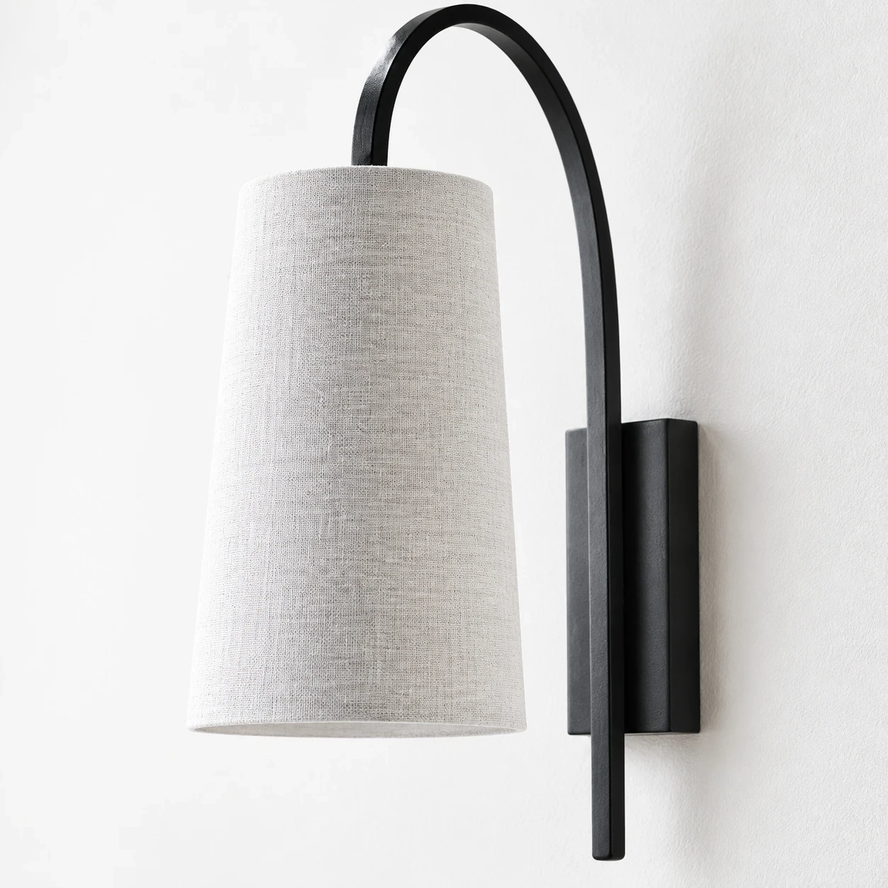 Close view of the woven fabric shade, curved arm, and rectangular black-iron wall plate