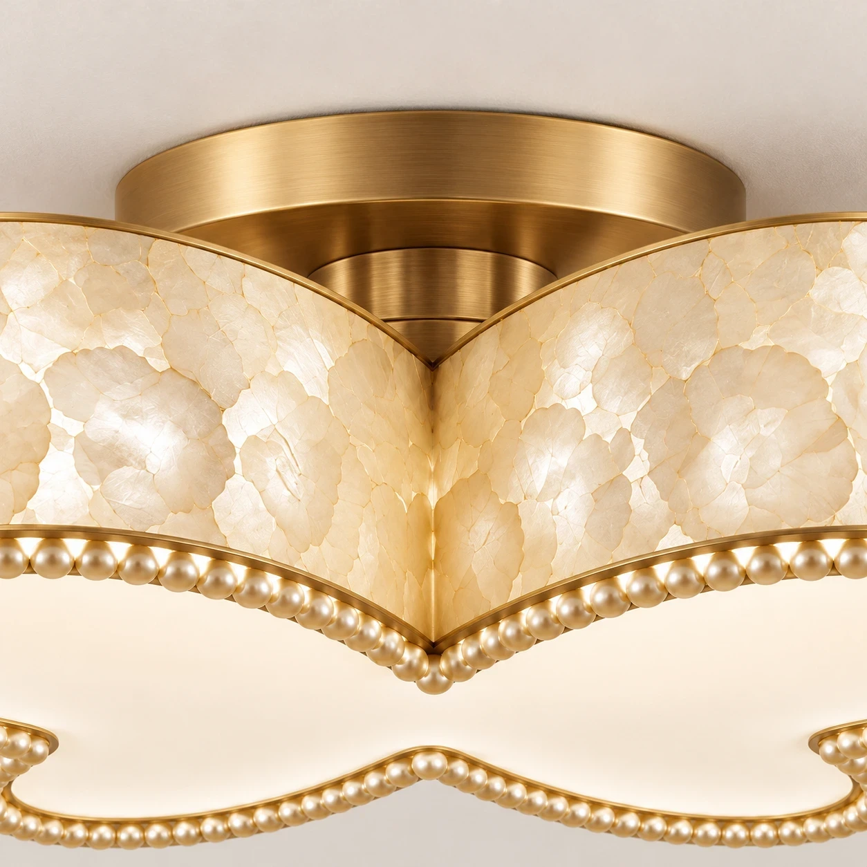 Close view of the ceiling mount, turned warm-tone metal cap, and warm-tone ceiling plate