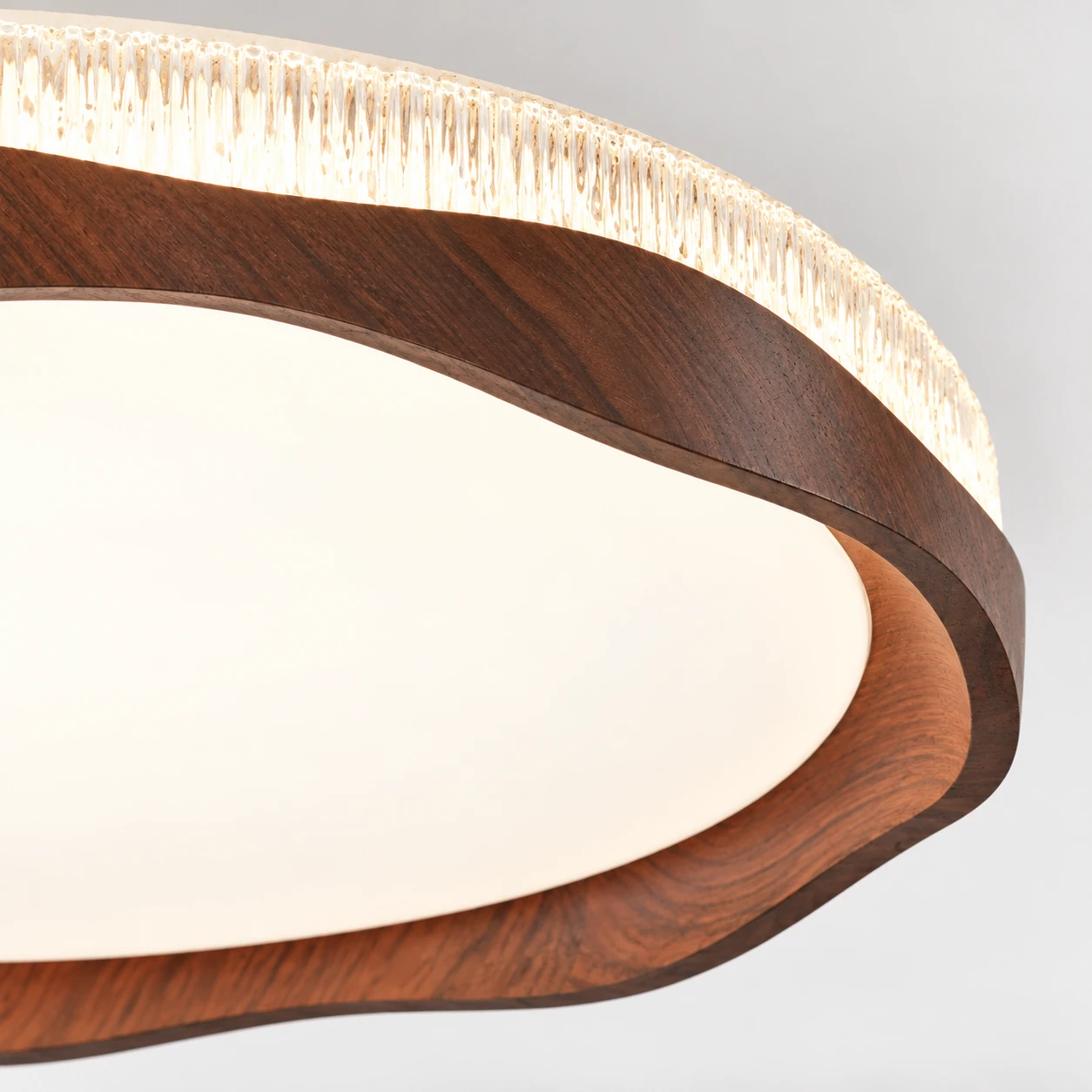 Close detail of the wavy walnut rim on the Marielle flush mount